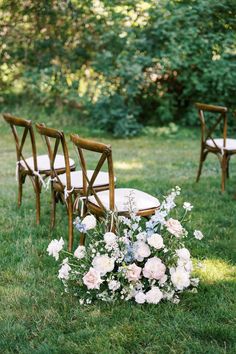 the chairs are set up in the grass for an outdoor ceremony with flowers and greenery