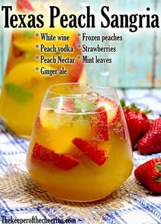 two glasses filled with drinks and strawberries on top of a blue table cloth next to some strawberries