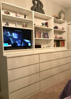 a white entertainment center with bookshelves and shelves on each side, along with a flat screen tv