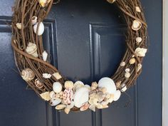 a wreath with seashells is hanging on the front door