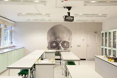 an empty room with tables and chairs in front of a large skull mural on the wall