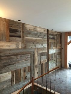 an empty room with wood paneling on the wall and stair railings to the second floor