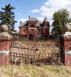 an old red brick house behind a gate