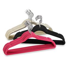 three different colored clothes hangers with metal clips on each side and one black, white, and pink