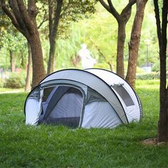 a tent pitched up in the grass next to trees