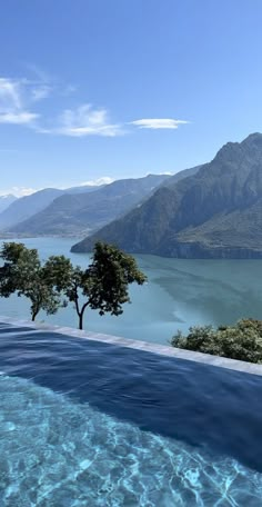 an outdoor swimming pool with mountains in the background and water reflecting off it's surface