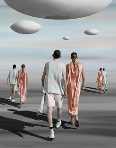 a group of people walking down a runway with white objects in the sky above them