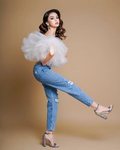 a woman in jeans and heels posing for the camera