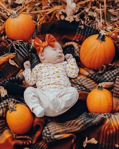 a baby laying on top of a pile of pumpkins