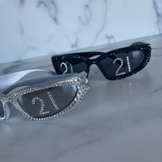 two pairs of sunglasses with diamond embellishments on them, one is black and the other is white