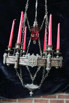 an old chandelier with red candles hanging from it's sides and chains