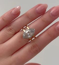 a woman's hand holding an engagement ring with a pear shaped diamond