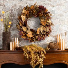 a wreath on top of a mantle next to candles