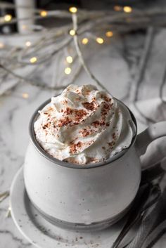 a cup filled with whipped cream on top of a white plate next to a christmas tree