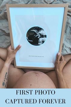 a pregnant woman holding up a framed photo with the words, first photo captured forever