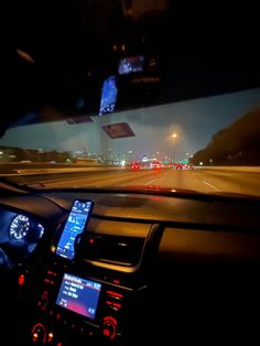 the dashboard of a car at night time with lights from cars driving on the road