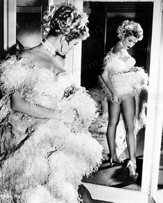 an old photo of two women dressed in feathery dresses and high heeled shoes