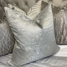 two silver pillows sitting on top of a bed