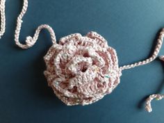 a crocheted flower on a blue surface with a white string attached to it