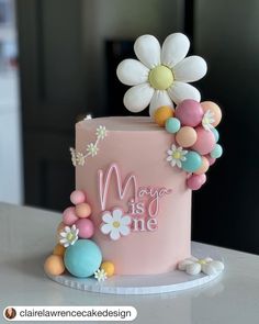 a pink cake with flowers and balloons on it's top that says may is one