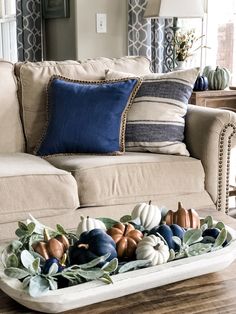 a tray filled with pumpkins sitting on top of a wooden table next to a couch