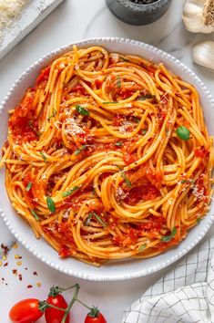 a white bowl filled with pasta and sauce on top of a table next to garlic