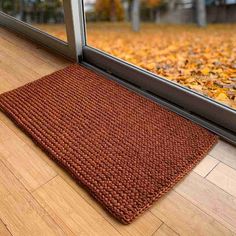 a door mat sitting on top of a wooden floor next to an open glass door