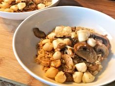 two white bowls filled with food on top of a wooden cutting board