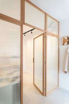 an open door leading to a white room with clothes hanging on the wall and a coat rack