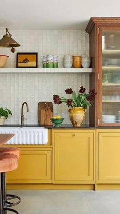 a kitchen with yellow cabinets and wooden stools