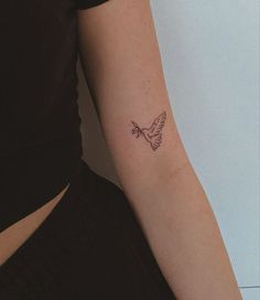 a small tattoo on the arm of a woman's left arm, with a bird flying above it