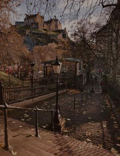 the stairs lead up to an old castle like building on top of a hill in autumn