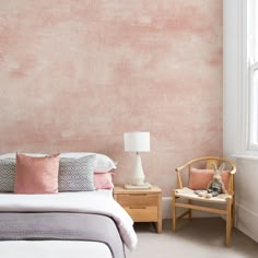 a bed room with a neatly made bed and a chair next to the window in front of it