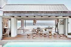 an open air swimming pool next to a beach house with a covered patio and dining area