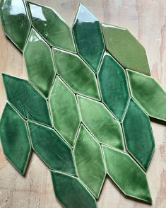 a green leaf shaped tile on a wooden surface with white and black dots in the center