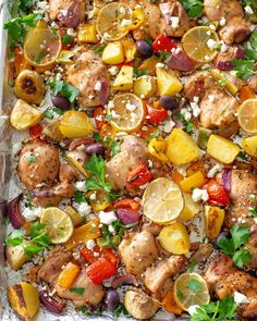 a sheet pan filled with chicken, lemons and other veggies on top of rice