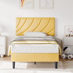 a bed with yellow headboard and foot board in a white room next to two pictures on the wall