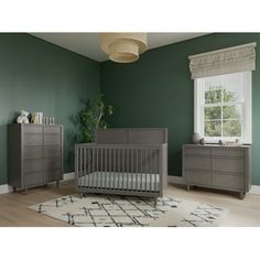 a baby crib and dresser in a room with green walls, rugs and windows