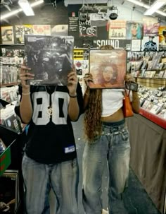 two people holding up cds in front of their faces