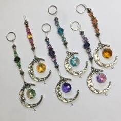 six different colors of beads hanging from metal hooks on a white surface with silver rings