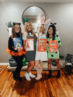 three women in bunny ears holding up some books while standing next to each other on a wooden floor