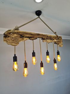 a light fixture made out of driftwood and hanging from the ceiling with five bulbs