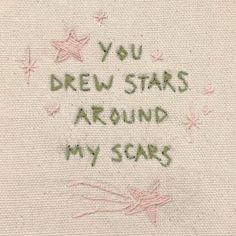 the embroidered message is written in green ink on a white piece of cloth with pink stars