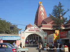 people are walking around in front of a small building with a clock tower on top