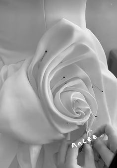 a woman is working on a white rose that has been made into a dress with the word love spelled in it