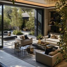 a living room filled with lots of furniture and plants in front of large sliding glass doors