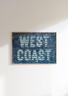 a blue and white sign that says west coast on the side of a wall in a room