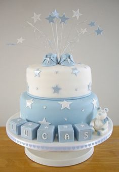 a blue and white baby shower cake with stars on the top, it is decorated with blocks that spell out congratulations