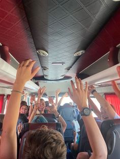 many people on a bus with their hands in the air