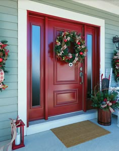 a red front door with two wreaths on the side and one is decorated for christmas